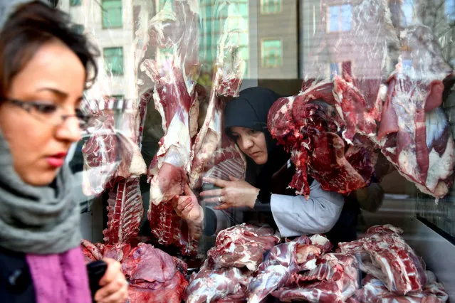 In this Tuesday, March 11, 2014 photo, butcher Zahra Shokouhi, center, works at her shop in downtown Tehran, Iran. Shokouhi, 45, a mother of three girls, learned butchery – a job held traditionally by men in Iranian society – from her husband and by working alongside him. She has surprised many passers-by in the last twelve years while working as a butcher in their shop next to a mosque in a conservative district in south of Tehran. (Photo by Ebrahim Noroozi/AP Photo)