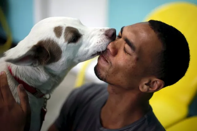 Mansai Conner, 21, is licked by a dog on the opening day of Dog Cafe, a coffee shop where people can adopt shelter dogs in Los Angeles, California, United States, April 7, 2016. (Photo by Lucy Nicholson/Reuters)