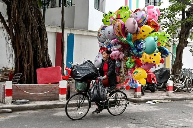 A street vendor rides a bicycle with balloons to sell on a street in Hanoi on February 1, 2024. (Photo by Nhac Nguyen/AFP Photo)