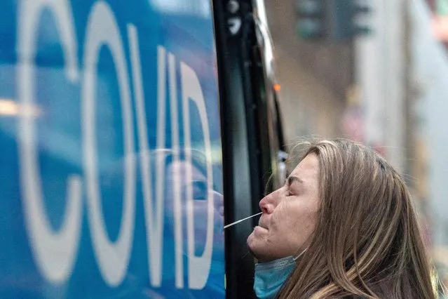 A woman takes a coronavirus disease (COVID-19) test at a pop-up testing site as the Omicron coronavirus variant continues to spread in Manhattan, New York City, U.S., December 27, 2021. (Photo by Jeenah Moon/Reuters)