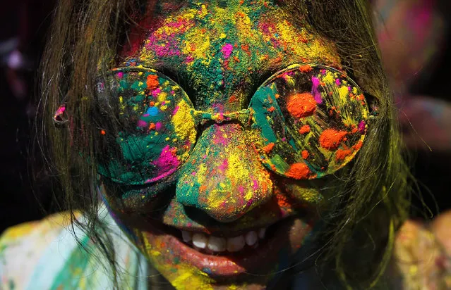 A woman, face smeared with colored powder, smiles during a religious spring festival Holi in Kuala Lumpur, Malaysia, Sunday, March 23, 2014. Holi, the Hindu festival of colors, is celebrated by people throwing colored powder and water at each other. (Photo by AP Photo)
