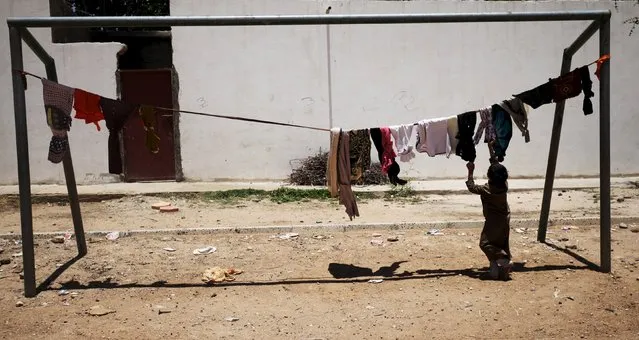 An internally displaced boy hangs laundry out to dry in a school playground in Sanaa May 17, 2015. (Photo by Mohamed al-Sayaghi/Reuters)