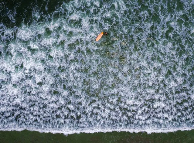 A man surfs in Maresias beach, Sao Sebastiao, Brazil, Sunday, November 28, 2021. The area's waves went virtually unridden until construction in the 1970s of a coastal highway, which surfing trailblazers followed to explore. (Photo by Andre Penner/AP Photo)