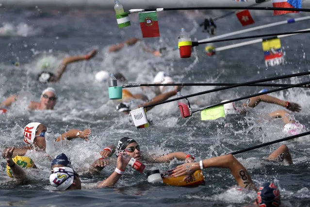 Swimmers reach for drink bottles while competing in the women's 10km open water swim at the World Swimming Championships in Yeosu, South Korea, Sunday, July 14, 2019. (Photo by Mark Schiefelbein/AP Photo)