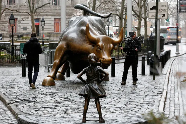 A camera man films a statue of a girl facing the Wall St. Bull, as part of a campaign by U.S. fund manager State Street to push companies to put women on their boards, in the financial district in New York, U.S., March 7, 2017. (Photo by Brendan McDermid/Reuters)