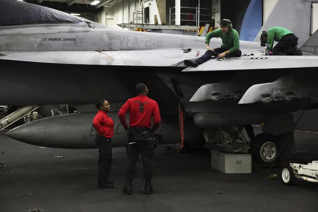 In this Tuesday, March 21, 2017 photograph, sailors work on an F-18 fighter jet on the USS George H.W. Bush as it travels through the Strait of Hormuz. (Photo by Jon Gambrell/AP Photo)