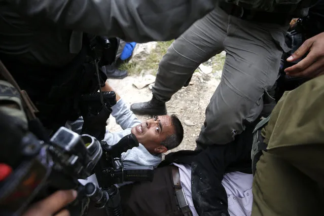 Israeli army troops arrests a protester during a protest to mark “National Land Day” near Kiryat Arba settlement in the West Bank city of Hebron, 30 March 2017. On 30 March 1976, Palestinians declared a general strike and held large demonstrations against land expropriations by Israeli authorities in the Galilee. This day has been marked as the National Land Day, Israel killed six Palestinians and injured and detained many others on that day. (Photo by Abed Al Hashlamoun/EPA)