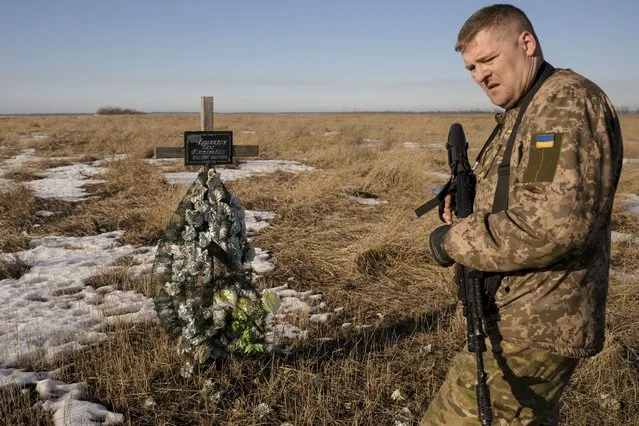 A Ukrainian serviceman walks by a cross in memory of a soldier killed near that spot in 2018, on a front line position outside Popasna, Luhansk region, eastern Ukraine, Monday, February 14, 2022. (Photo by Vadim Ghirda/AP Photo)