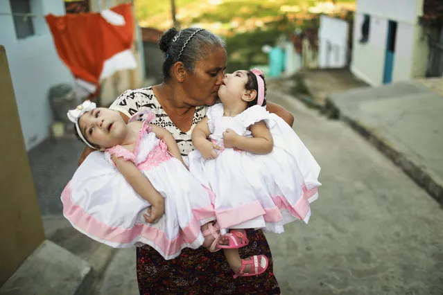 Grandmother Maria Jose holds her twin granddaughters Heloisa and Heloa Barbosa, both born with microcephaly, outside of their house as they pose for photos at the twins' one-year birthday party on April 16, 2017 in Areia, Paraiba state, Brazil. The twins turned one-year old on April 14th but mother Raquel decided to hold their birthday party on Easter Sunday. Raquel said she contracted the Zika virus during her pregnancy. As many of the babies born with microcephaly, believed to be linked to the Zika virus, approach or have already turned one year old in the region, doctors and mothers are adapting and learning treatments to assist the children. Many suffer a plethora of difficulties including vision and hearing problems with doctors now labeling the overall condition as congenital Zika syndrome. Authorities recorded thousands of cases in Brazil in which the mosquito-borne Zika virus may have led to microcephaly in infants. Microcephaly results in an abnormally small head in newborns and is associated with various disorders. (Photo by Mario Tama/Getty Images)