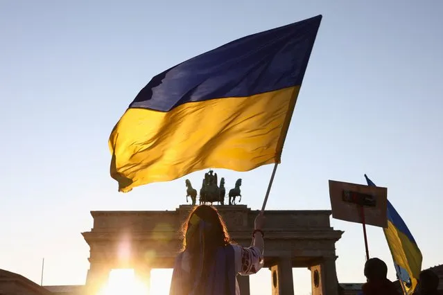 A person holds a Ukrainian flag during an anti-war demonstration “Stop the War. Peace and Solidarity for the People in Ukraine” against Russia's invasion of Ukraine, next to the Brandenburg Gate in Berlin, Germany, March 13, 2022. (Photo by Christian Mang/Reuters)