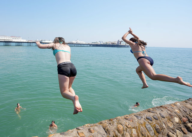 Youngsters dive into the sea enjoy a warm day on Brighton Beach, UK on June 26, 2024. The thermometer is expected to reach up to 30°C in some parts of the UK this week. (Photo by Ioannis Alexopoulos/London News Pictures)