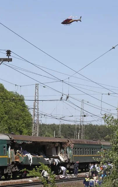 A helicopter flies above a passenger train damaged in a collision with a freight train in Moscow region May 20, 2014. The passenger train on its way to Moldova collided with a freight train near Moscow on Tuesday, killing at least four people and injuring 15, a spokeswoman for Russia's Emergencies Ministry said. The reason for the collision, near the town of Naro-Fominsk 55 km (34 miles) southwest of Moscow, was not immediately clear. (Photo by Grigory Dukor/Reuters)