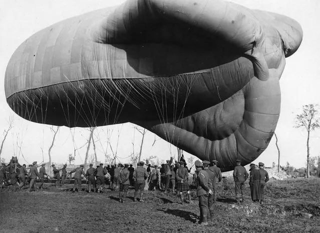 A returning observation balloon. A small army of men, dwarfed by the balloon, are controlling its descent with a multitude of ropes. The basket attached to the balloon, with space for two people, can be seen sitting on the ground. (Photo by National Library of Scotland via The Atlantic)