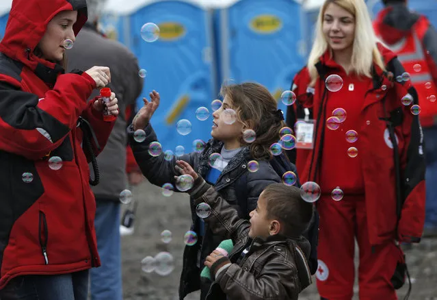Children play with bubbles blown by volunteers as migrants and refugees are registered by the authorities before continuing their train journey to western Europe at a refugee transit camp in Slavonski Brod, Croatia, February 10, 2016. (Photo by Darrin Zammit Lupi/Reuters)