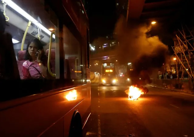 A woman sits on a bus as fire burns in the middle of the street during an anti-government demonstration in Tsuen Wan in Hong Kong, China, November 10, 2019. (Photo by Shannon Stapleton/Reuters)