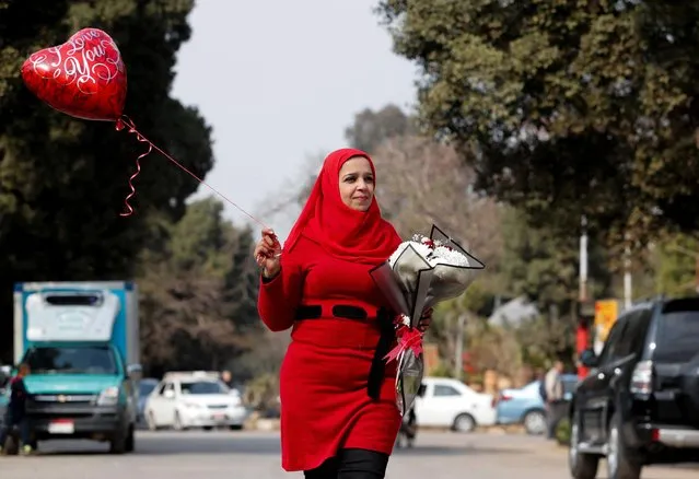 A woman carries flowers and a balloon while celebrating Valentine's Day in Cairo, Egypt on February 14, 2022. (Photo by Mohamed Abd El Ghany/Reuters)