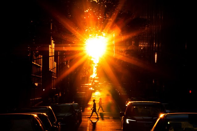 People cross a street at sunset in Manhattan, New York City on June 10, 2024. (Photo by Charly Triballeau/AFP Photo)