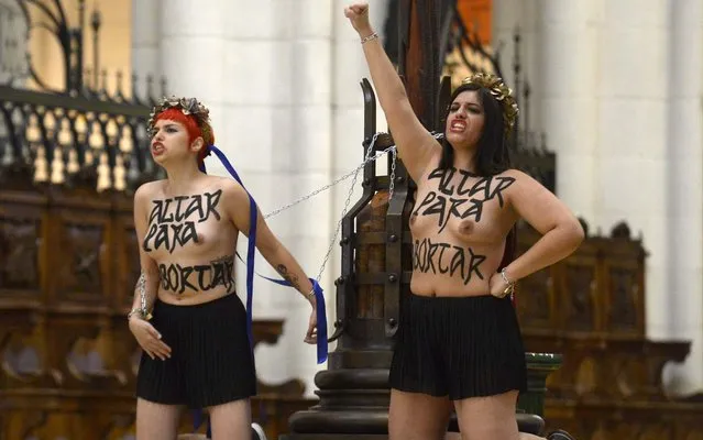 Bare-breasted activists of feminist movement Femen protest, chained to a cross, against a reform of the country's abortion law at the Almudena Cathedral in Madrid on June 13, 2014. The General Council of the Judiciary (GCJ) held today an extraordinary plenary session to decide its report on the draft law on abortion. (Photo by Gerard Julien/AFP Photo)