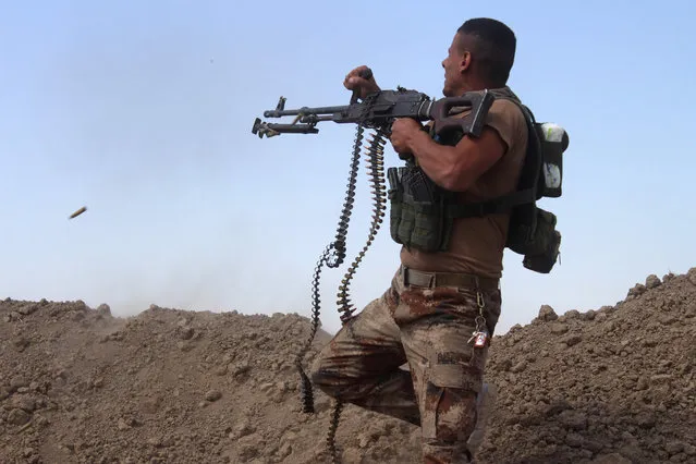 A member of the Iraqi pro-governement forces fires his weapon on a front line in the Albu Huwa area, south of Fallujah near the Euphrates river, on May 31, 2016, during an operation aimed at retaking areas from the Islamic State group. Iraqi forces launched an offensive a week ago to recapture Fallujah, which became an IS group stronghold after its fighters seized the city in January 2014. (Photo by Moadh Al-Dulaimi/AFP Photo)