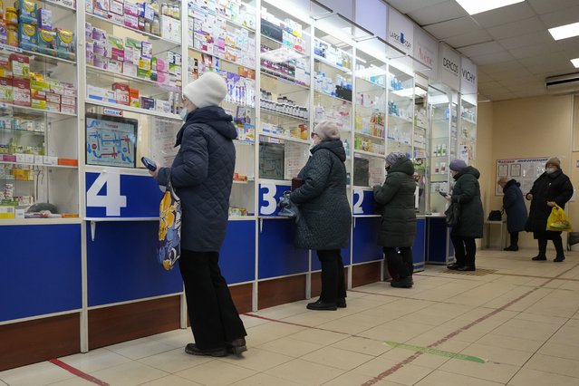 Customers stand at the windows buying medicines in a pharmacy in St. Petersburg, Russia, Friday, April 1, 2022. (Photo by AP Photo/Stringer)