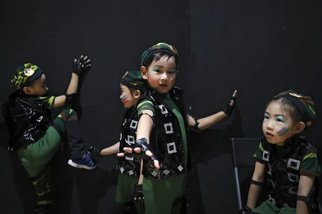 In this Friday, June 23, 2017 photo, kindergarten children wearing military costumes with PLA badges play as they prepare at backstage for a performance during a graduation ceremony in Beijing. (Photo by Andy Wong/AP Photo)