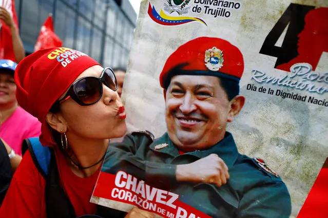 A pro-government supporter gestures as she hold a sign of Venezuela's late President Hugo Chavez during a rally of members of the education sector in Caracas, Venezuela June 14, 2016. (Photo by Ivan Alvarado/Reuters)