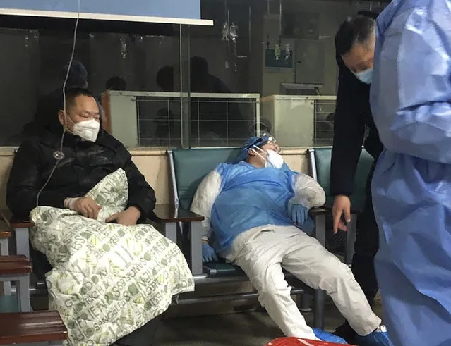 In this January 23, 2020, photo, a medical worker rests in a chair next to a patient at a hospital in Wuhan in central China's Hubei Province. As Beijing instates one of the largest quarantines in modern history, locking down over 50 million people in Hubei province, questions are swirling around the provincial government's sluggish initial response. (Photo by AP Photo/China Stringer Network)