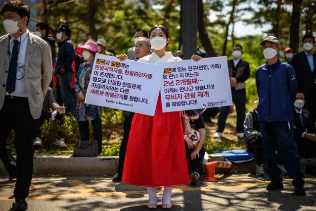 An activist holds placards calling for improved relations between Japan and South Korea as she stands on a nearby roadside with other spectators outside the National Assembly, before the inauguration ceremony of South Korea's new president Yoon Suk-yeol in Seoul on May 10, 2022. (Photo by Anthony Wallace/AFP Photo)