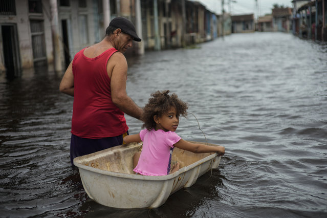 Jesus Hernandez guides his granddaughter Angelina via a container through a street flooded in the passing of Hurricane Helene, in Batabano, Mayabeque province, Cuba, Thursday, September 26, 2024. (Photo by Ramon Espinosa/AP Photo)