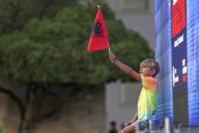 A boy holds an Albanian flag outside the Prime Minister's office during an anti-government rally in Tirana, Albania, on Thursday, July 7, 2022. The Albanian opposition rallied Thursday in the capital Tirana calling for the resignation of the government which they blame for corruption and inflicting poverty. (Photo by Franc Zhurda/AP Photo)