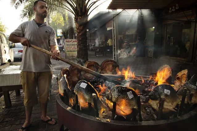 An Iraqi man cooks traditional Masgouf fish on a barbecue for sale in the Karada market July 02, 2014.  Masgouf, one of the national dishes of Iraq is a grilled carp seasoned with olive oil, rock salt, tamarind and ground turmeric. (Photo by Scott Nelson for the Washington Post)