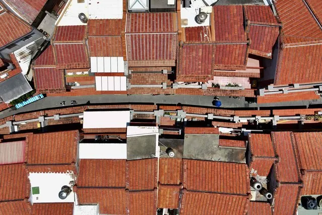 This aerial photo taken on May 30, 2022 shows people walking down a narrow lane in a local area in the town of Magong on the Penghu islands. In the sleepy fishing towns on the Penghu islands, many locals are sanguine despite the frequent – and noisy – reminders of the military threat by neighbouring China. (Photo by Sam Yeh/AFP Photo)