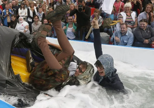 Participants fall after sliding down on a float along a chute to cross a pool of water and foam during the “Letniy Gornoluzhnik” (Summer mountain puddle rider) festival at the Bobroviy Log Fun Park near the Siberian city of Krasnoyarsk, Russia, August 23, 2015. (Photo by Ilya Naymushin/Reuters)