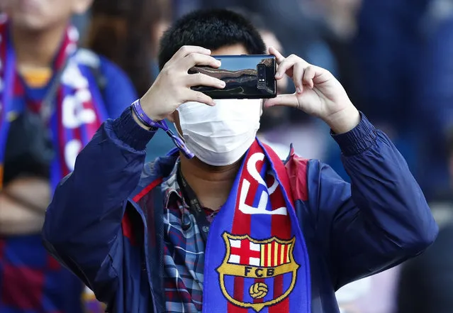 A Barcelona fan wears a face mask in an attempt to protect there self from the coronavirus uses his mobile prior a Spanish La Liga soccer match between Barcelona and Real Sociedad at the Camp Nou stadium in Barcelona, Spain, Saturday, March 7, 2020. (Photo by Joan Monfort/AP Photo)