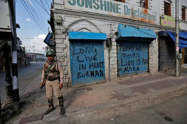 An Indian policeman stands guard in front of closed shops painted with graffiti during a curfew in Srinagar July 12, 2016. (Photo by Danish Ismail/Reuters)