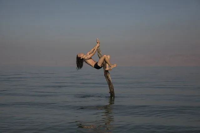 A camper climbs on a tree trunk at Metsuke Dragot beach of the Dead Sea, 23 November 2020. Known for their therapeutic properties, health benefits and mineral-rich mud, Dead Sea beaches lure tourists in from all over the world. Metsuke Dragot beach is located next to an Israeli checkpoint that separates the West Bank and Israeli Territory. Barely having any supervision, the beach attracts people of all ages to escape the hustle and bustle of city life and to connect with nature. The beach is also known to be a nudist beach. (Photo by Abir Sultan/EPA/EFE)