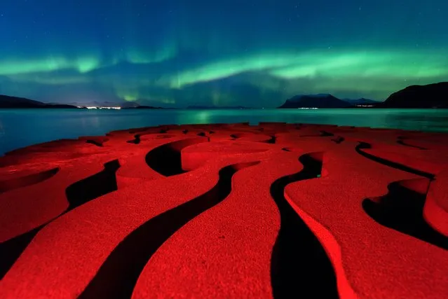 “Seven Magic Points”. The rusty red swirls of the circular, iron sculpture Seven Magic Points in Brattebergan, Norway mirror the rippling aurora above. (Photo by Rune Engebø/Royal Observatory Greenwich’s Astronomy Photographer of the Year 2016/National Maritime Museum)