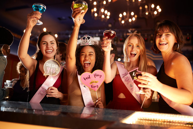 Group of female friends celebrating with bride on hen party in bar. (Photo by Alamy Stock Photo)