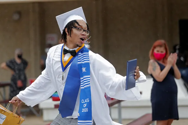 Graduate Cameron Magee of the New Orleans Charter Science and Math High School class of 2020 celebrates after receiving his diploma at a drive-in graduation ceremony as a result of the COVID-19 pandemic, outside Delgado Community College in New Orleans, Wednesday, May 27, 2020. Students and family got out of their cars to receive diplomas one by one, and then held a parade of cars through city streets. (Photo by Gerald Herbert/AP Photo)