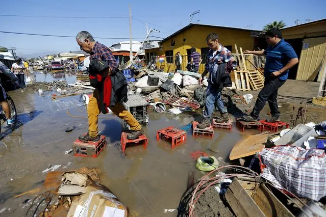 People cross a damaged street on debris after an earthquake hit areas of central Chile, in Coquimbo city, north of Santiago, Chile, September 17, 2015. (Photo by Ivan Alvarado/Reuters)