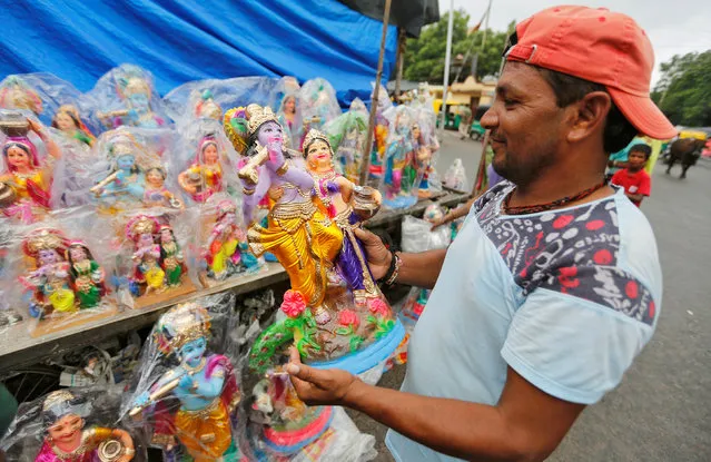 A man holds idols of Hindu Lord Krishna and his consort Radha before buying them at a roadside market on the occasion of Janmashtami festival marking the birth of Lord Krishna, in Ahmedabad, India, August 25, 2016. (Photo by Amit Dave/Reuters)