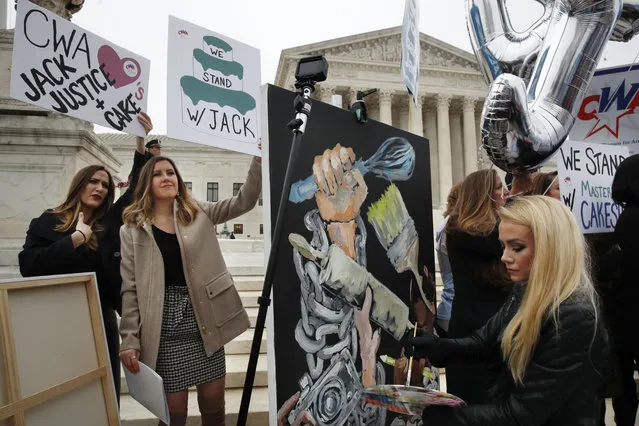 As Janae Stracke, left, and Annabelle Rutledge, both with Concerned Women for America, hold up signs, as Jessica Haas, of Indianapolis, paints during a rally with supporters of cake artist Jack Phillips outside of the Supreme Court which is hearing the “Masterpiece Cakeshop v. Colorado Civil Rights Commission” today, Tuesday, December 5, 2017, in Washington. (Photo by Jacquelyn Martin/AP Photo)