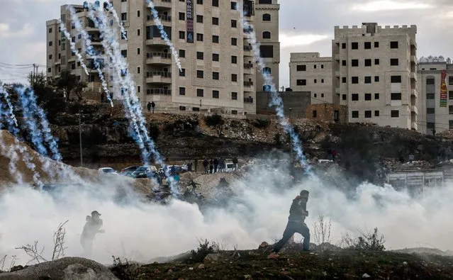 Palestinian protesters run from falling tear gas canisters fired by Israeli forces during clashes near an Israeli checkpoint in the West Bank city of Ramallah on December 10, 2017, following the US president's controversial recognition of Jerusalem as Israel's capital.
New protests flared in the Middle East and elsewhere over US President Donald Trump's December 6 declaration of Jerusalem as Israel's capital, a move that has drawn global condemnation and sparked days of unrest in the Palestinian territories. (Photo by Abbas Momani/AFP Photo)