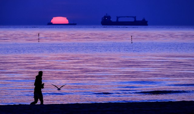 A man runs during sunrise at the beach in Heringsdorf on the Baltic island of Usedom, Germany, 13 April 2025. (Photo by Hannibal Hanschke/EPA/EFE)