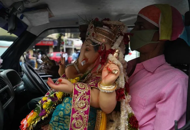 A devotee wearing a protective mask transports an idol of Hindu god Ganesh to his home on the first day of the ten-day-long Ganesh Chaturthi festival, amid the coronavirus disease (COVID-19) outbreak, in Mumbai, India on August 22, 2020. (Photo by Hemanshi Kamani/Reuters)