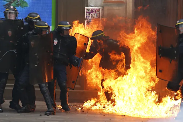 A French riot police officer is surrounded by flames, during a demonstration against the controversial labour reforms of the French government in Paris on September 15, 2016. Opponents of France's controversial labour reforms took to the streets on September 15, 2016 for the 14th time in six months in a last-ditch bid to quash the measures that lost the Socialist government crucial support on the left. Scores of flights in and out of France were cancelled as air traffic controllers went on strike to try to force the government to repeal the changes that became law in July. (Photo by Thomas Samson/AFP Photo)