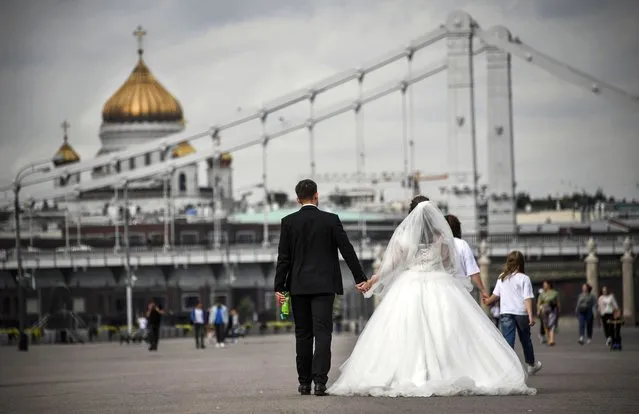 A couple walks along an embankment of the Moskva river in front of Christ the Savior Cathedral in Moscow on August 24, 2020. (Photo by Alexander Nemenov/AFP Photo)
