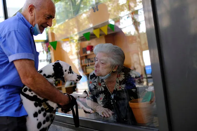 Maria de Concepcion Illa, 89, who lives in a care home, blows a kiss to Menta, the dog of her neighbour Antoni (L), 70, as they talk through a glass front at the Centre Parc nursing home after Catalonia's regional authorities announced restrictions to contain the spread of the coronavirus disease (COVID-19), in Barcelona, Spain on August 27, 2020. (Photo by Nacho Doce/Reuters)