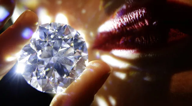 A 102.34, carat, D colour and flawless white diamond held by a model is displayed at Sotheby's auction house in London, Thursday, February 8, 2018. The diamond is the world largest known round brilliant diamond to have achieved “perfection in all critical criteria – Colour, Clarity, Cut and Carat”, and is expected to reach considerably over 33.7 million dollars by private sale in London. (Photo by Alastair Grant/AP Photo)