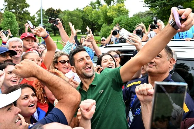 Serbia's Novak Djokovic gets selfies with his supporters outside the Government House  in Melbourne on January 30, 2023, after winning the Australian Open tennis tournament's mens' singles final against Greece's Stefanos Tsitsipas. (Photo by Saeed Khan/AFP Photo)